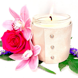 An all natural soy candle is wrapped in a pale blush pink leather with 3 silver cone shaped studs