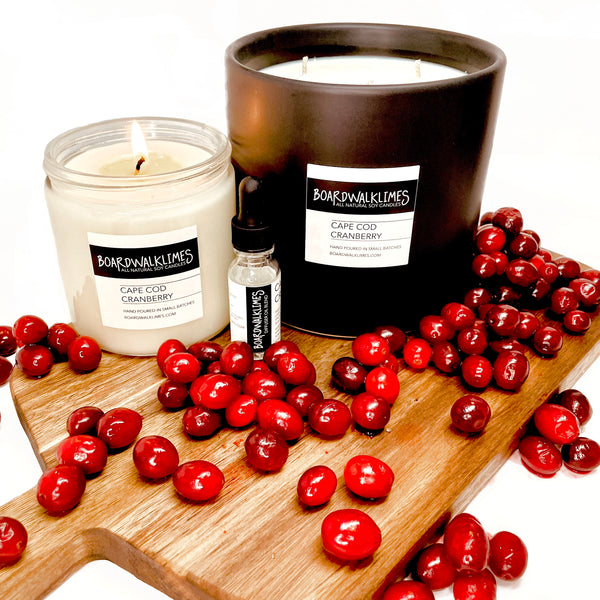 Fall scented candles and diffuser oils in cranberry and apple scented autumn notes in a clear glass jar and a large 3-wick coffee table size black ceramic vase