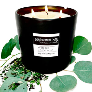 A large 3 cotton wick all natural soy candle with spa fragrances is in a handmade black ceramic container