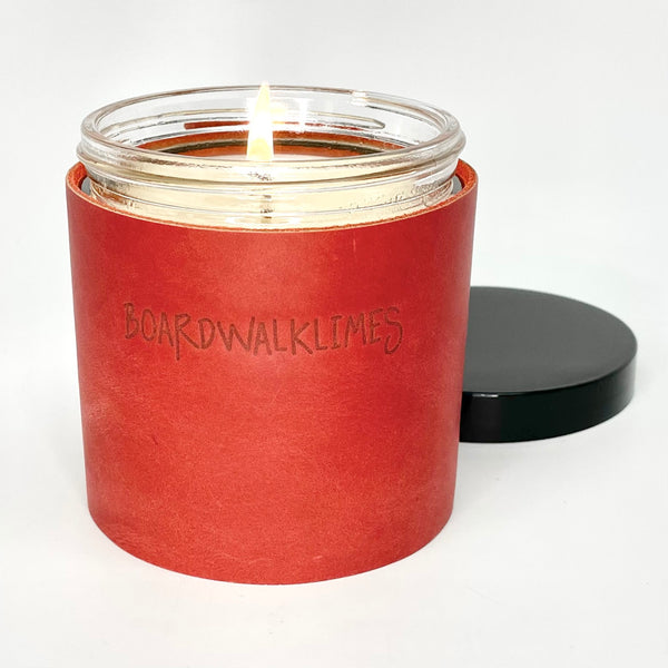 An all natural soy candle is wrapped in a red leather with 2 oil rubbed black studs