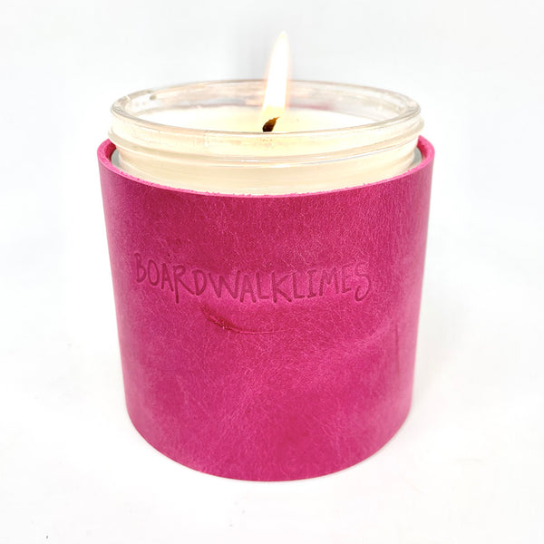 Scented soy candle wrapped in a bright pink leather sleeve with three gold cone shaped studs