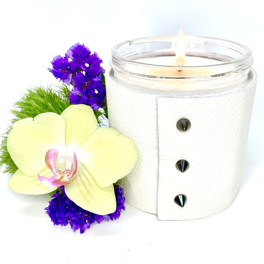 Large 1-wick luxury scented soy candle wrapped in fine white leather sleeve with 3 cone shaped studs and a shiny black lid