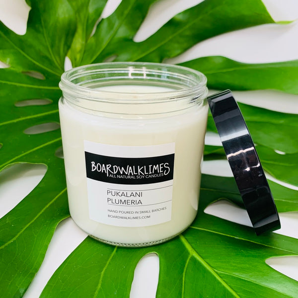Hawaiian notes of plumeria fill this floral soy candle in a clear glass say with a shiny black modern lid