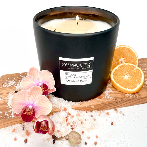 large 3 cotton wick all natural soy candle with the fragrances of orchids, set salt and citrus is in a handmade black ceramic container