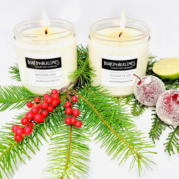 two winter soy candles in clear glass jars with shiny black lids in pine and eucalyptus scents with a fruity citrus twist.